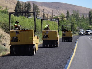 Three pneumatic rollers seating chips on a roadway